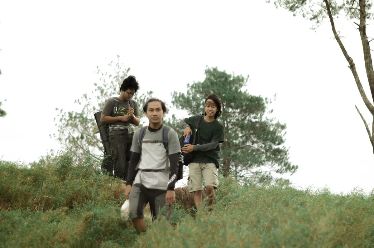 Three friends walking down a green hillside together